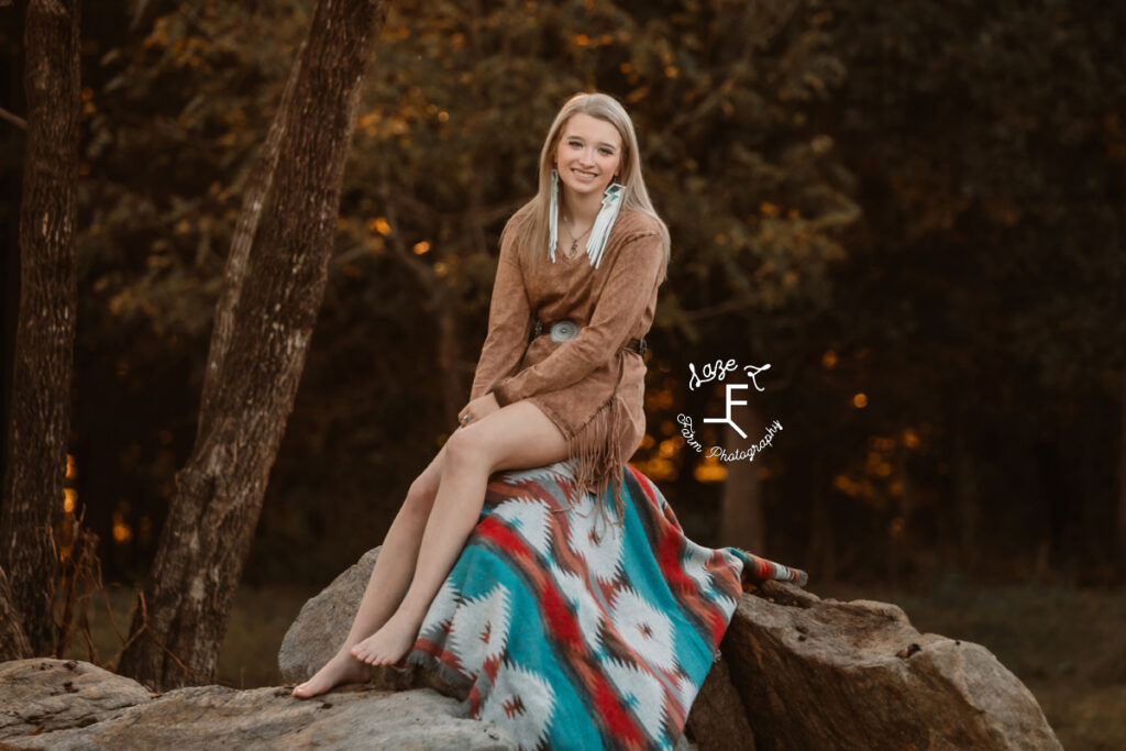 blond model sitting on rock with Aztec blanket