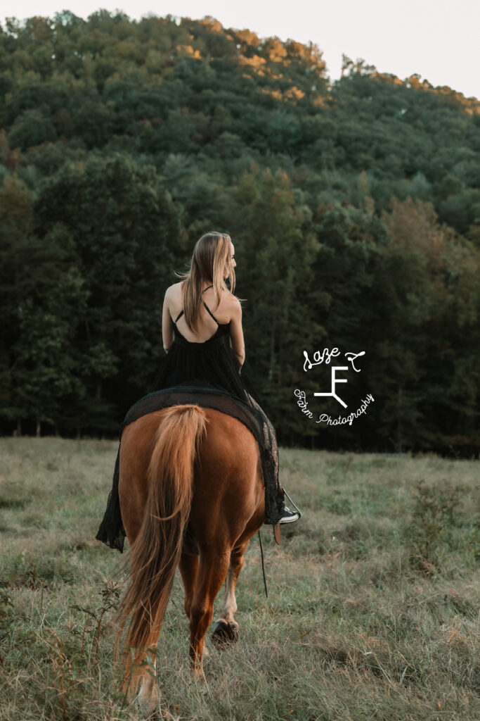 brunette model riding horse in long black dress