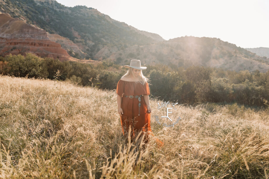 blond cowgirl in rust color dress in front of canyon