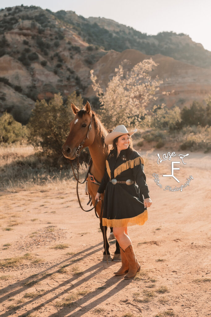 brunette cowgirl in blue and gold dress with horse