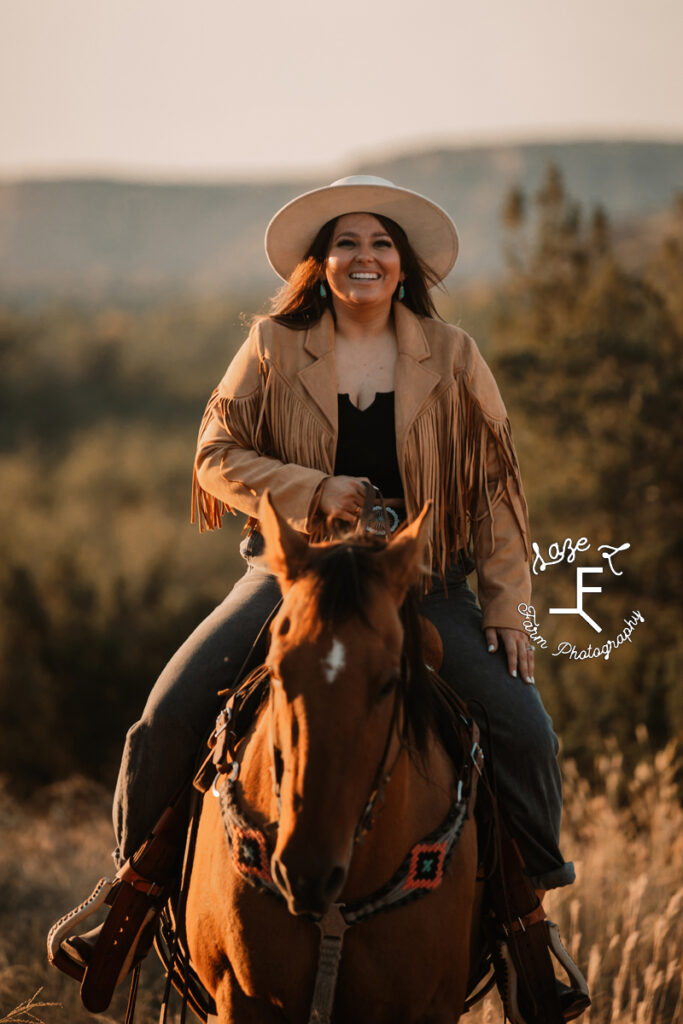 brunette cowgirl in fringe jacket riding horse