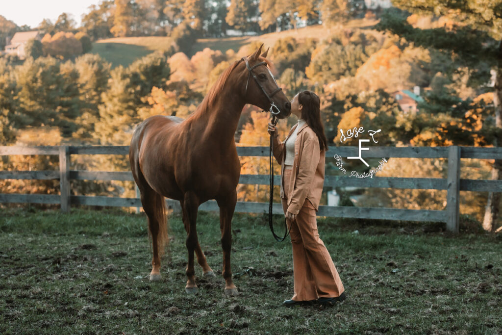sister in orange kissing her horse on the nose