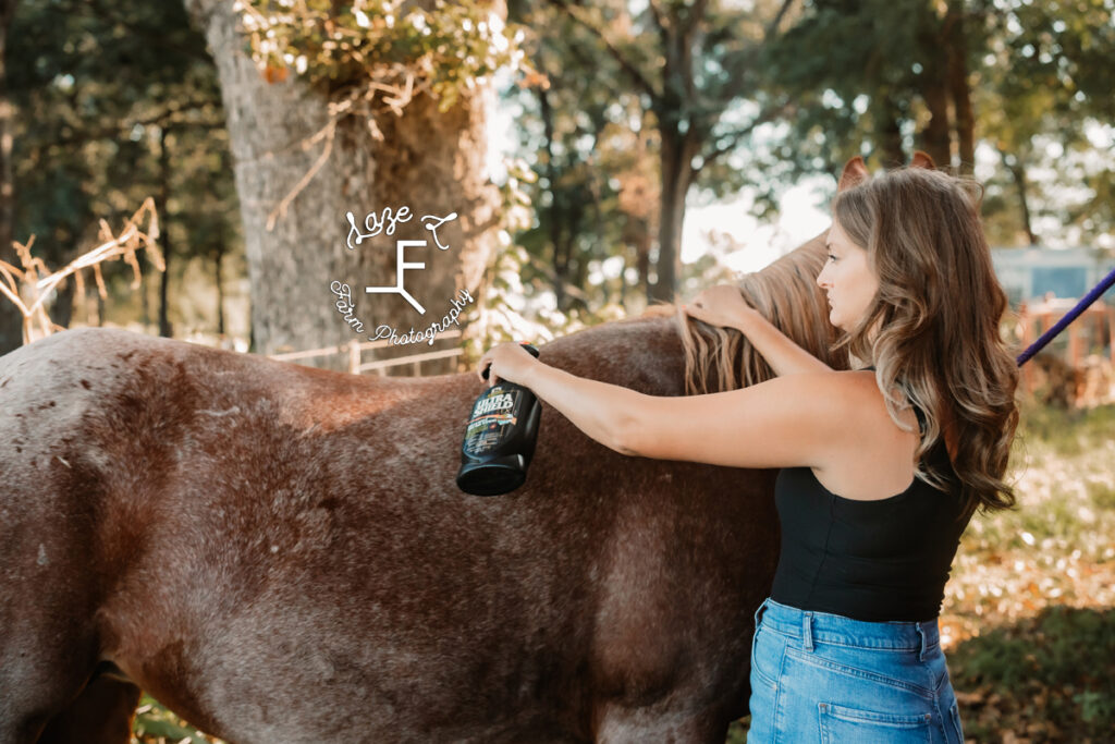 lydia spraying fly spray on horse