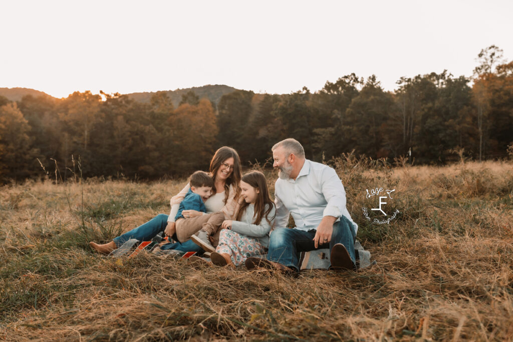 family sitting on blanket laughing