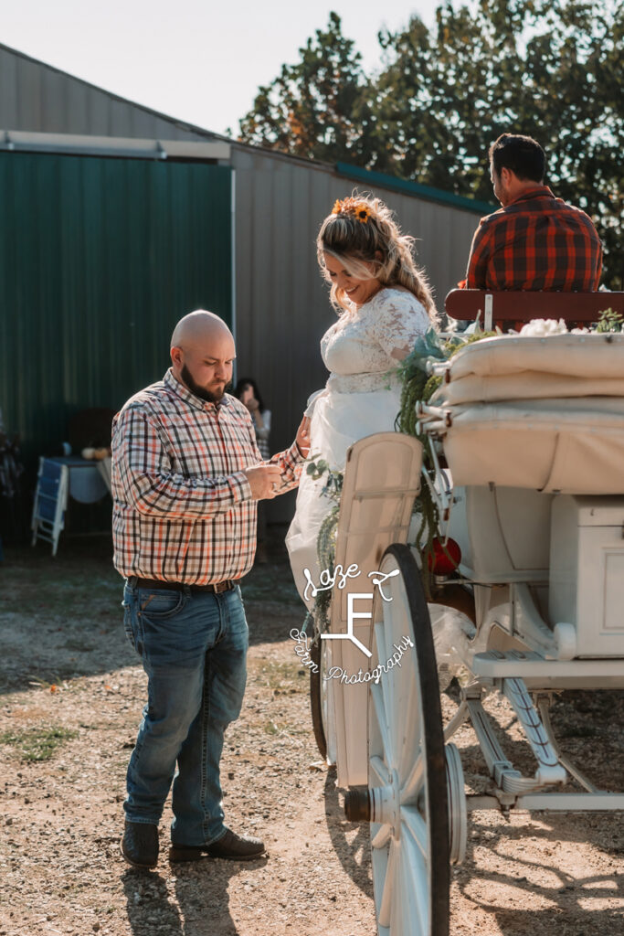 groom helping bride get out of carriage