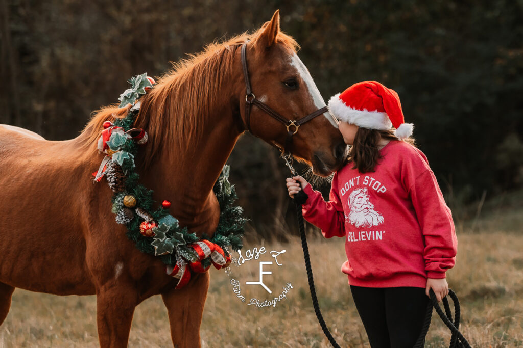 sister in Christmas sweatshirt and horse wearing Christmas wreath