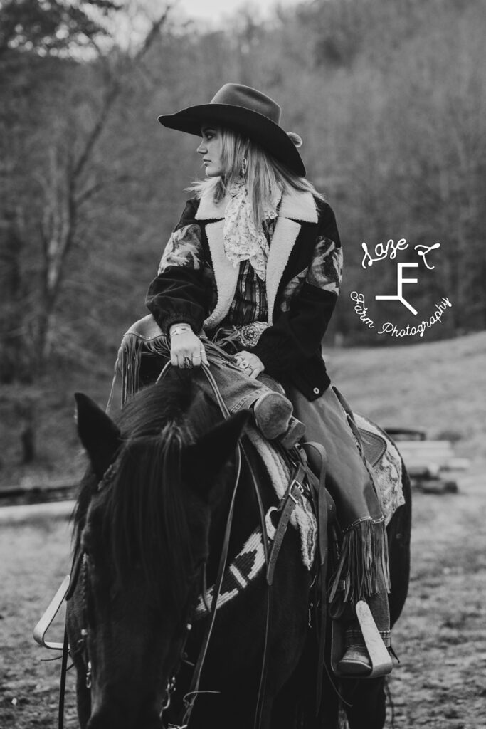 Cowgirl riding black horse in black and white