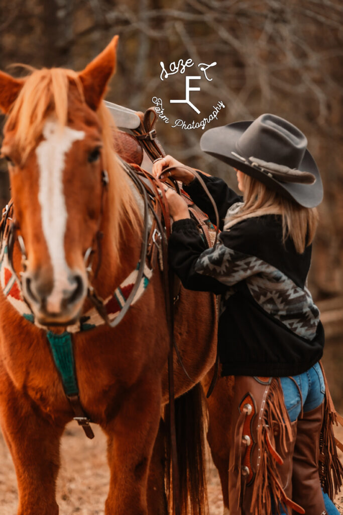 Cowgirl tacking up red horse