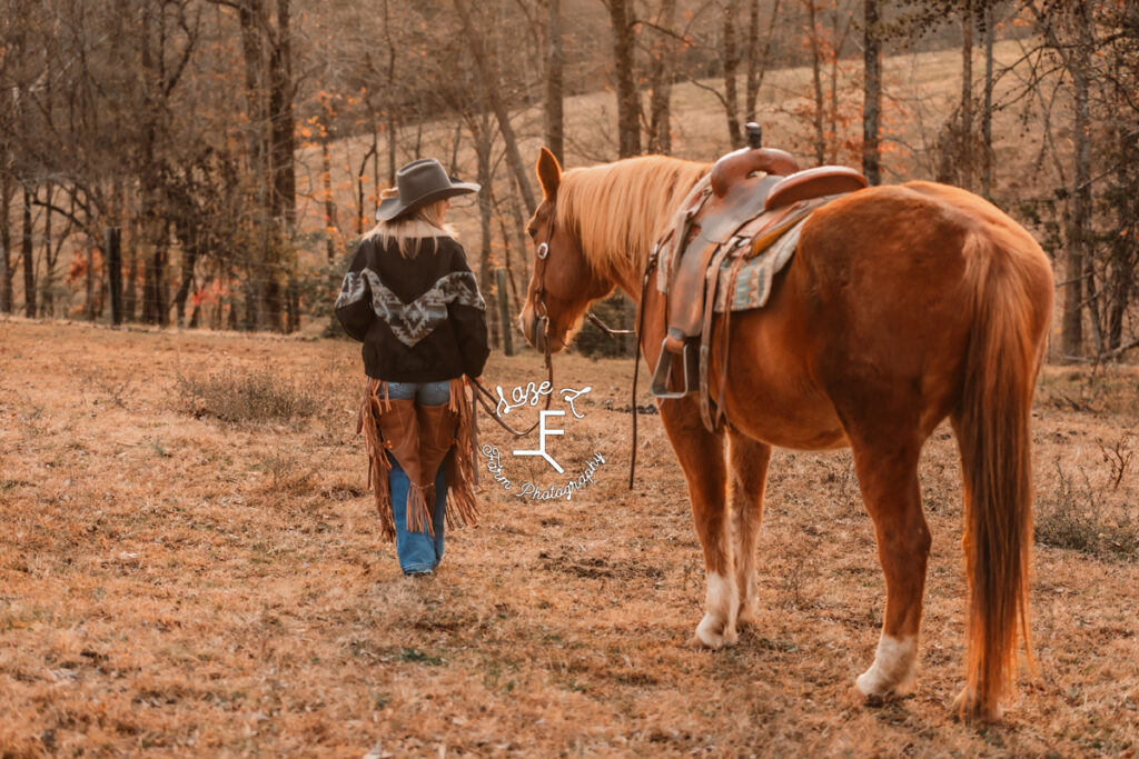 Cowgirl walking away leading red horse