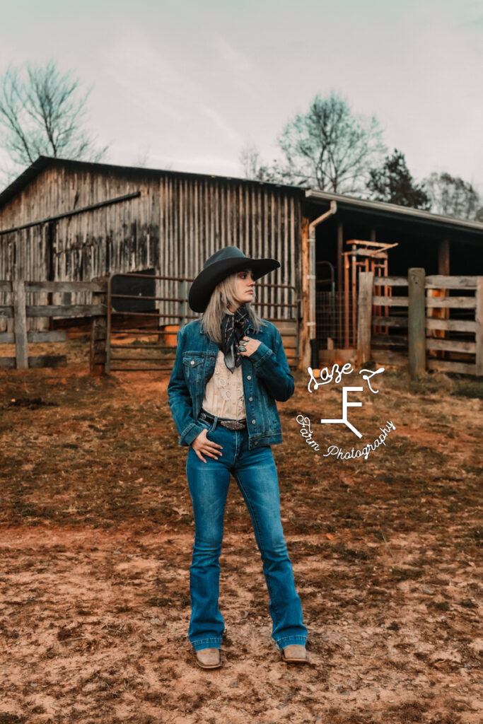 Cowgirl in front of old barn looking left