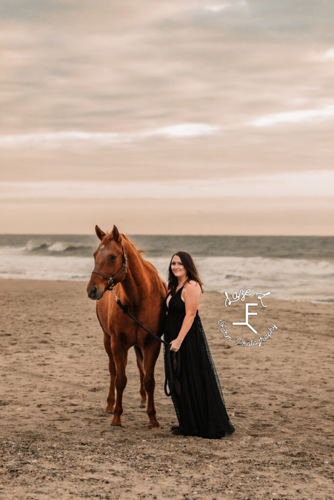 cowgirl in black dress on beach with older mare