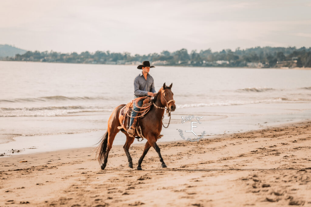 Cowboy riding on beach in CA