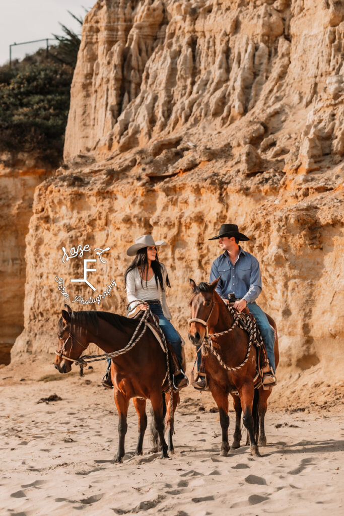 Couple riding horses on beach