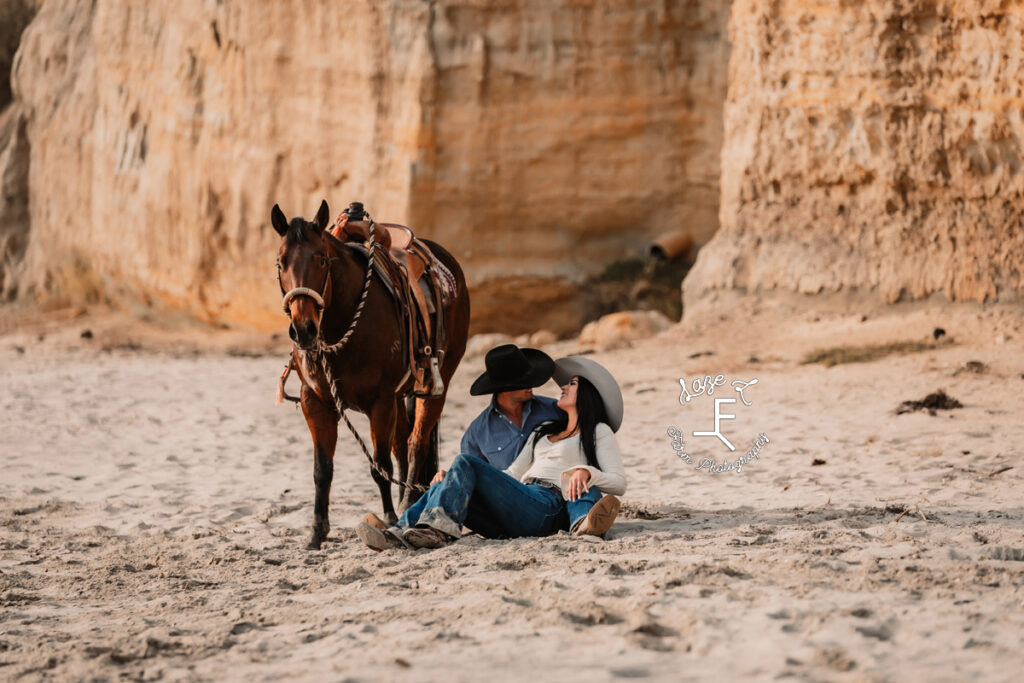 couple sitting on beach with horse