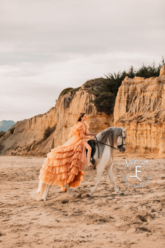 model riding white horse on beach