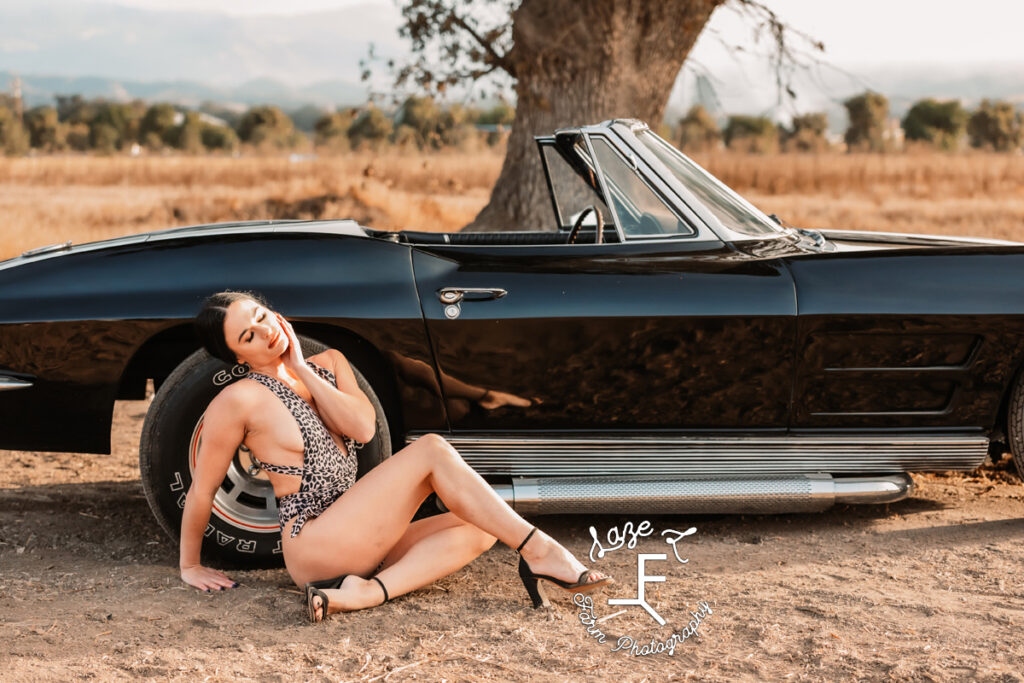 model in body suit in front of corvette