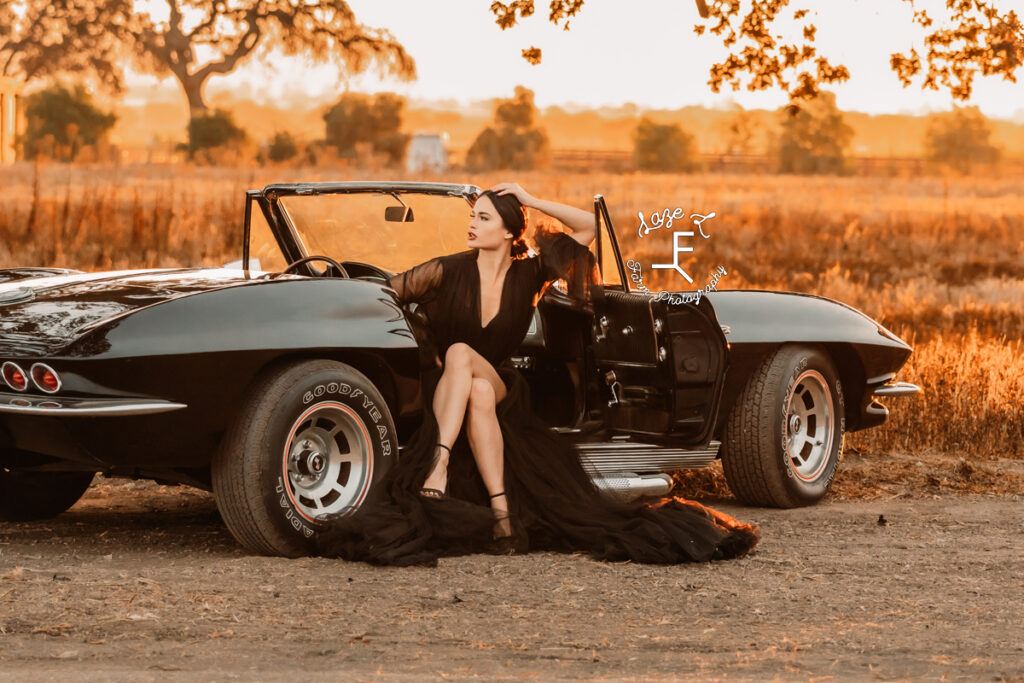 model in black dress sitting in black corvette looking left 