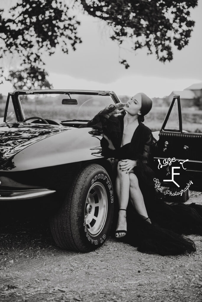 model sitting in corvette in black and white