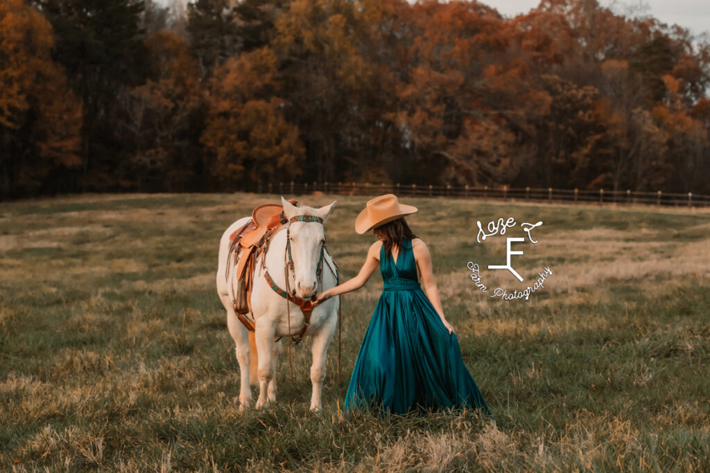 cowgirl in aqua dress walking with white horse