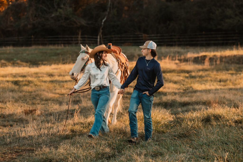 Cowgirl and boyfriend walking with white horse