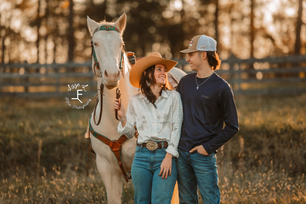 cowgirl and boyfriend looking at each other with white horse