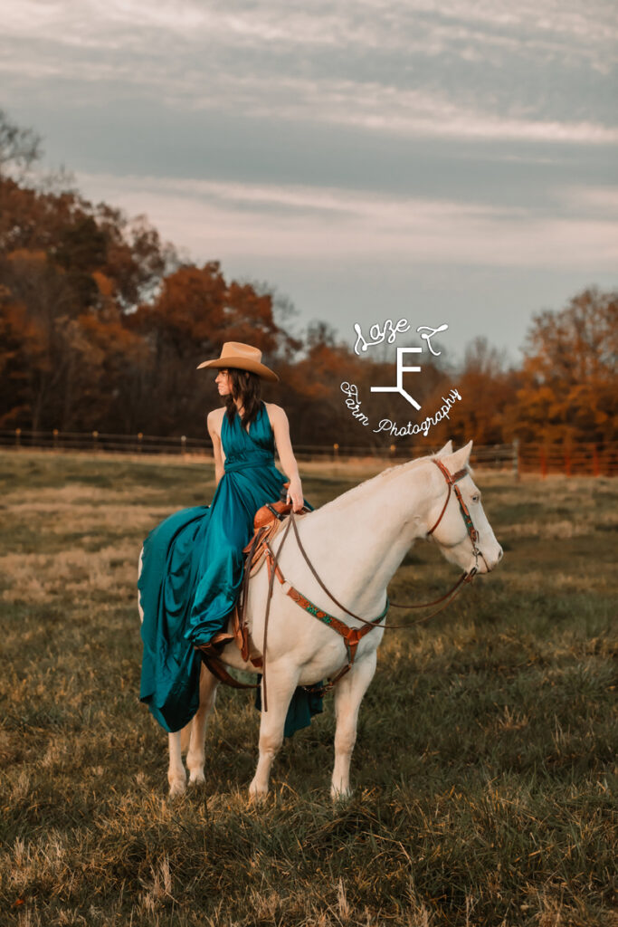 cowgirl sitting on white horse looking to the right