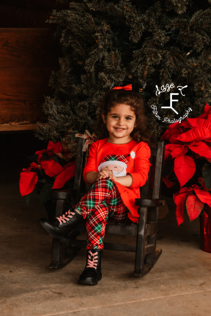 little girl sitting in rocking chair at Christmas tree