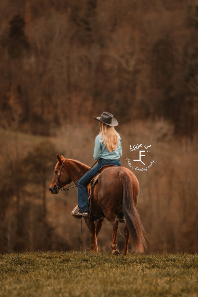 Cowgirl riding a red mare away from the camera