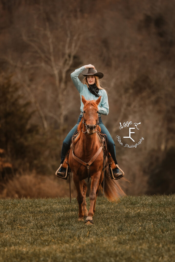 cowgirl hanging on to hat riding toward the camera