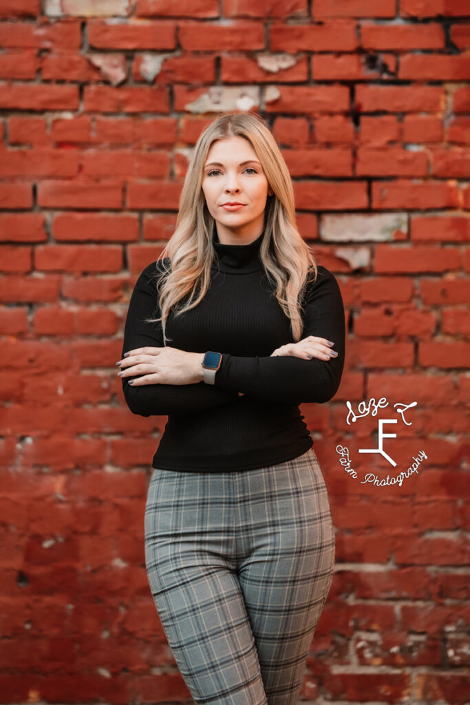 Sam standing with arms crossed in front of red brick