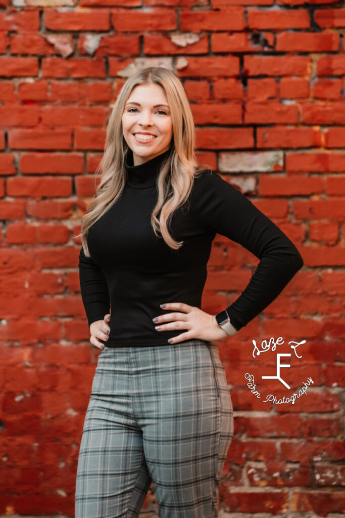 Sam standing smiling in front of red brick