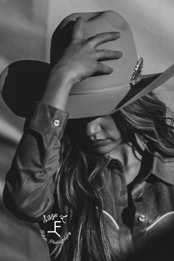 model with hand on hat looking down in black and white