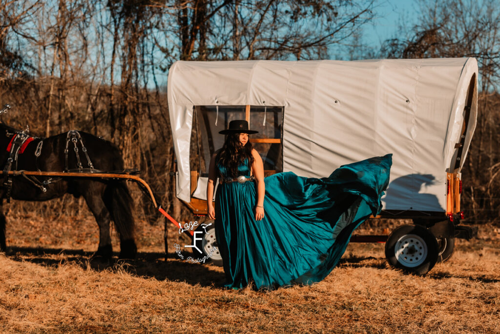 model in turquoise dress in front of wagon