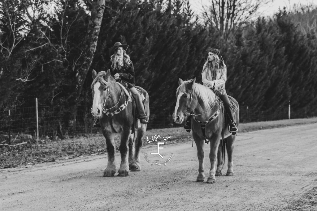 2 models riding Gus and Dolly down dirt road in black and white