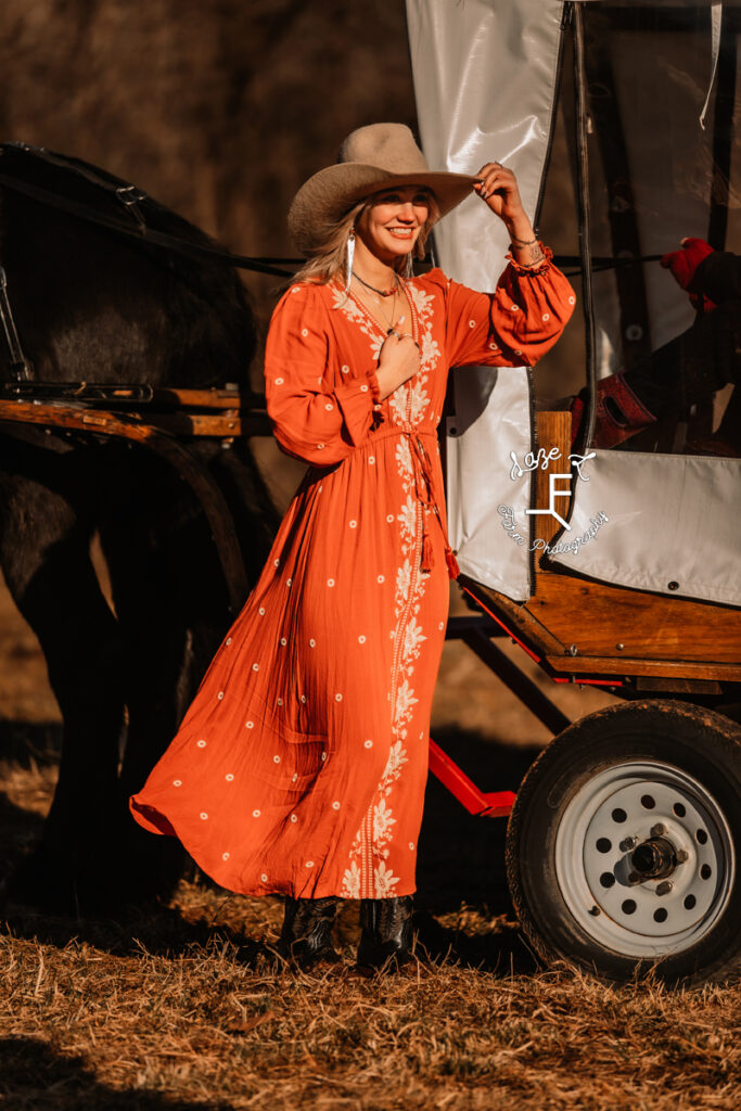 model wearing orange dress in front of covered wagon