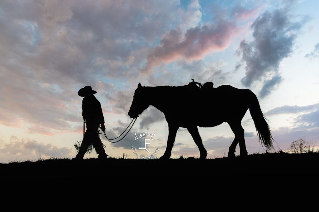 Sunset sillhoutte cowgirl walking her horse