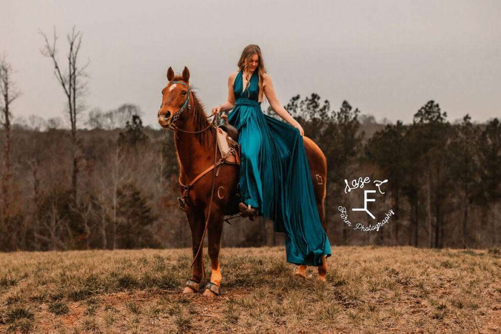 cowgirl in turquoise dress on horse back