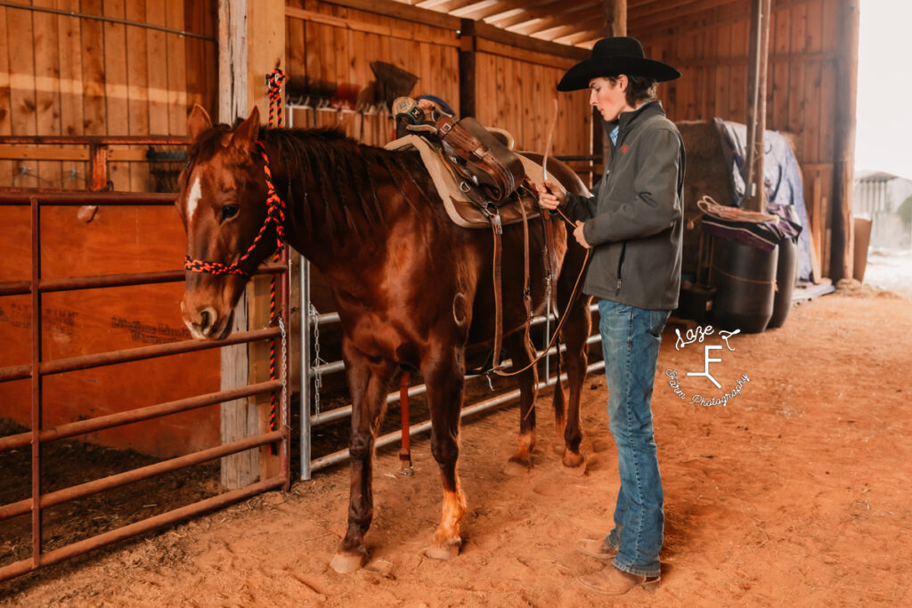 cowboy tacking up his horse