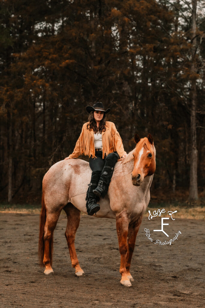 Amy sitting on red roan with legs crossed over one side