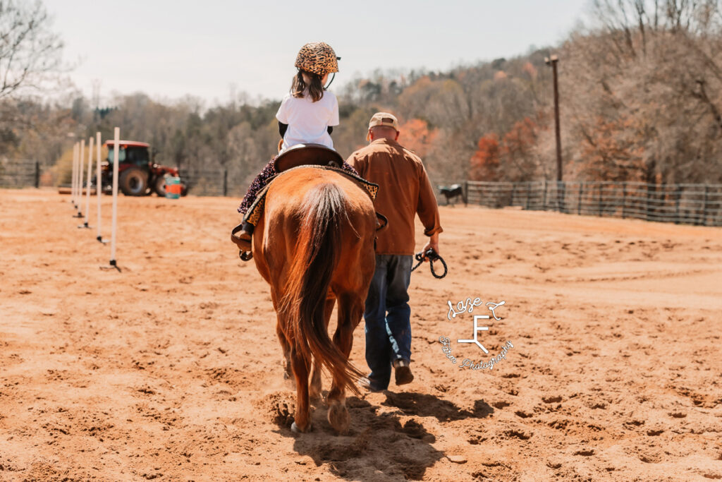 little rider on brown horse being led by dad