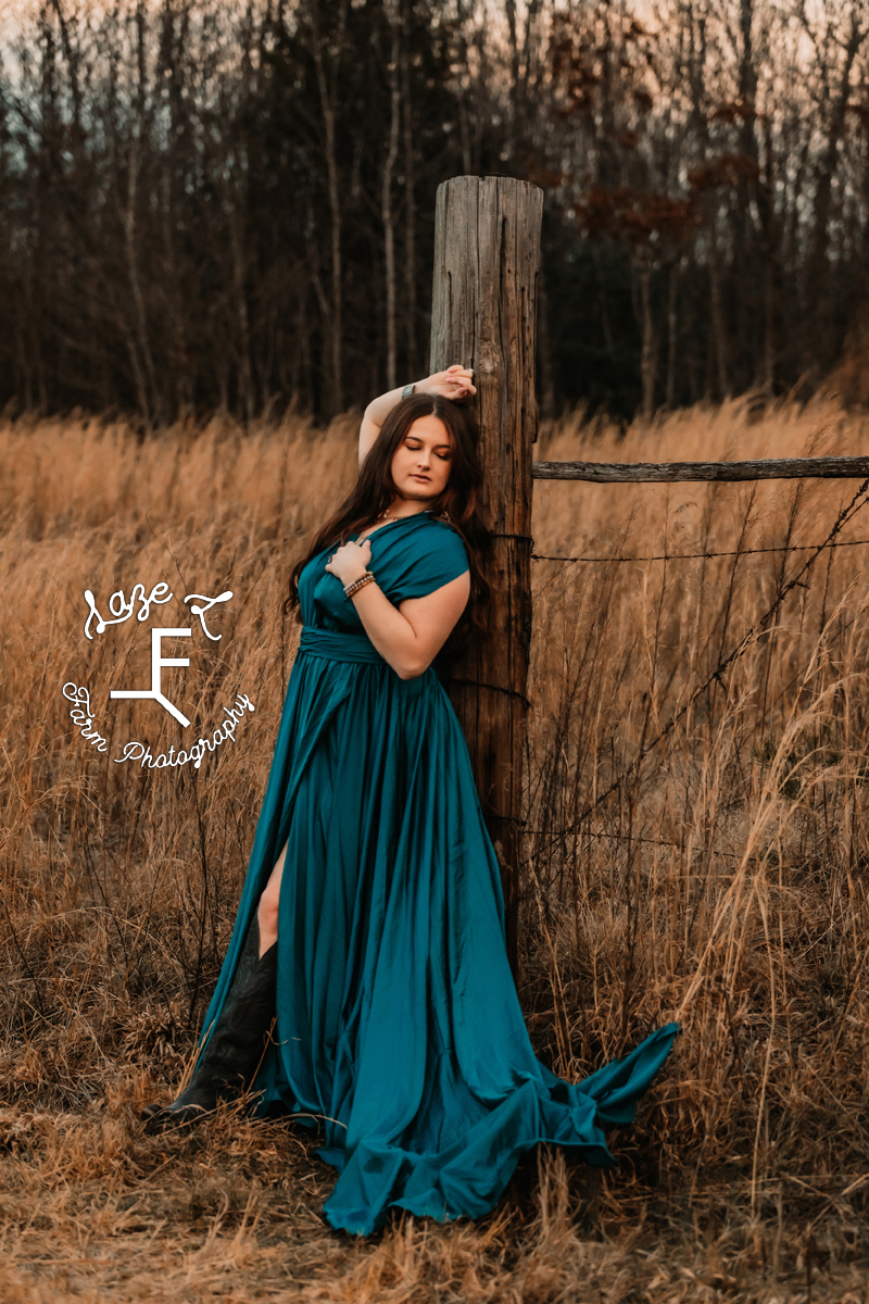 Savannah in turquoise dress against fence post