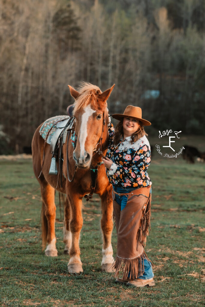 Deanna wearing chaps and flower shirt standing with Gus