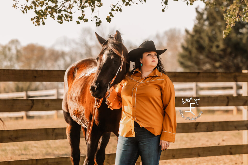 Kody with her mare in an orange shirt and black hat