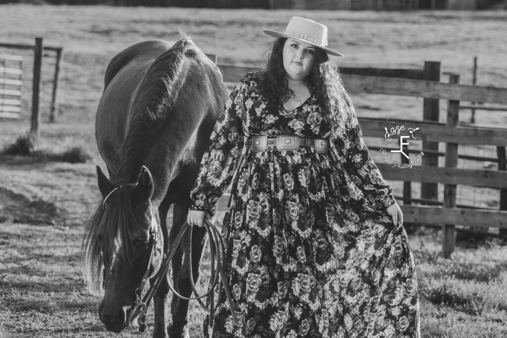 Kody in a floral print dress walking with her mare in black and white