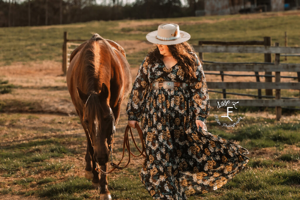 Kody in a floral print dress walking with her mare