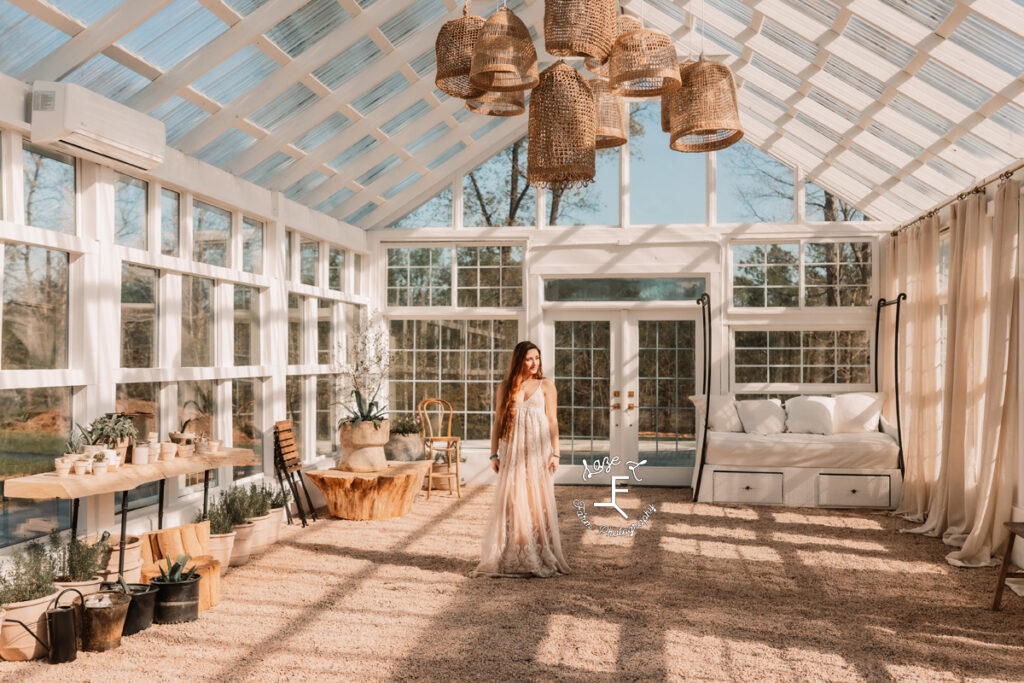 Bella in cream lace dress standing in middle of greenhouse