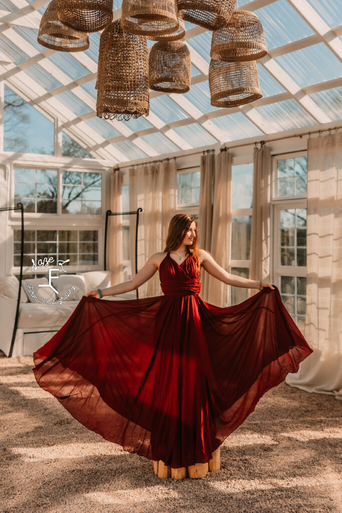 Bella in deep red dress standing