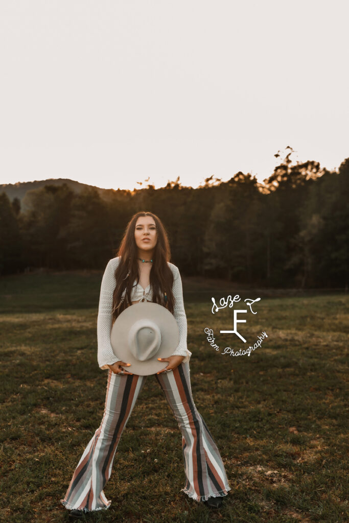 Halle holding white hat at sunset