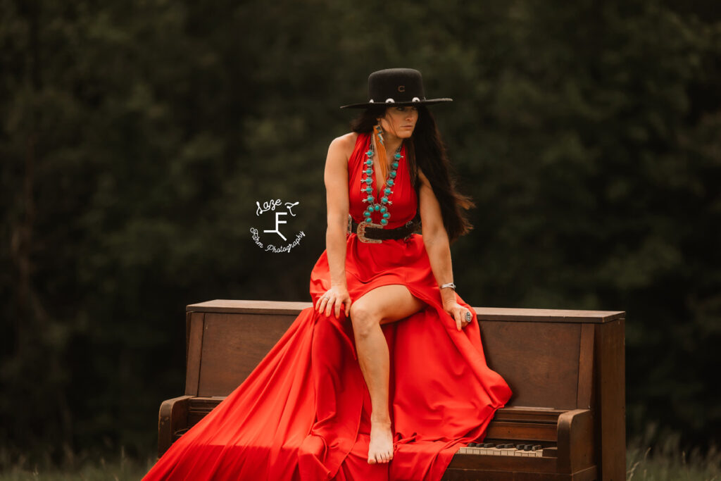 cowgirl with horse sitting on a piano with a red parachute dress