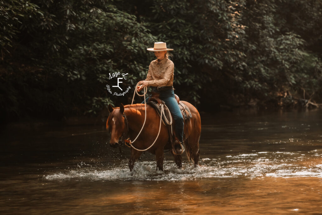 cowgirl riding horse in river